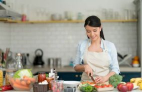 A woman chopping vegetables in a bright kitchen, gaining skills from the best chef classes in Bangalore for home cooks.