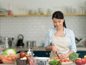 A woman chopping vegetables in a bright kitchen, gaining skills from the best chef classes in Bangalore for home cooks.